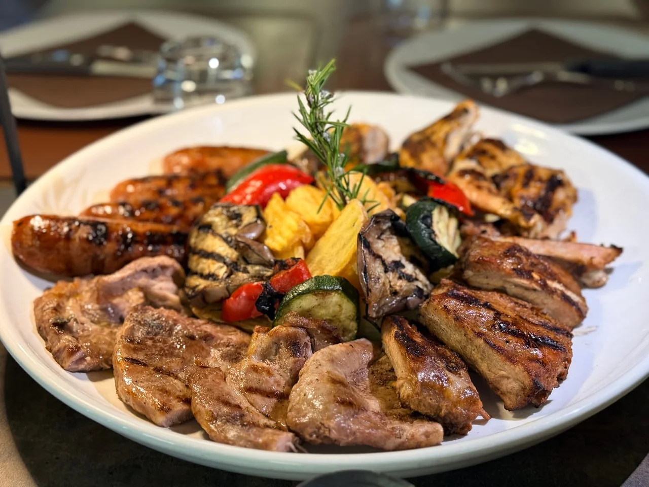 A mixed grill plate with sausages, chicken, ribs and vegetables