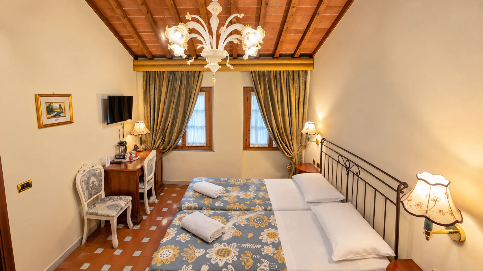 A Classic room with twin beds, floral bedspreads, a writing desk and a terracotta ceiling with exposed beams