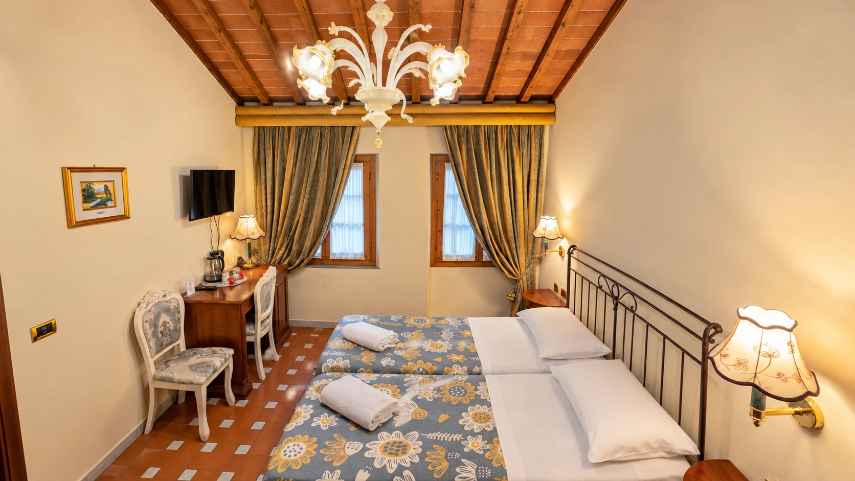 A Classic room with twin beds, floral bedspreads, a writing desk and a terracotta ceiling with exposed beams