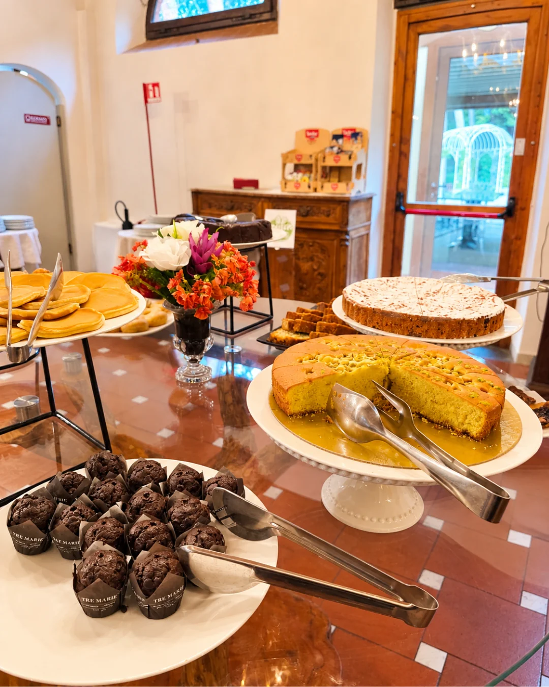 Muffin al cioccolato, pancake e torta al pistacchio sul tavolo rotondo di cristallo