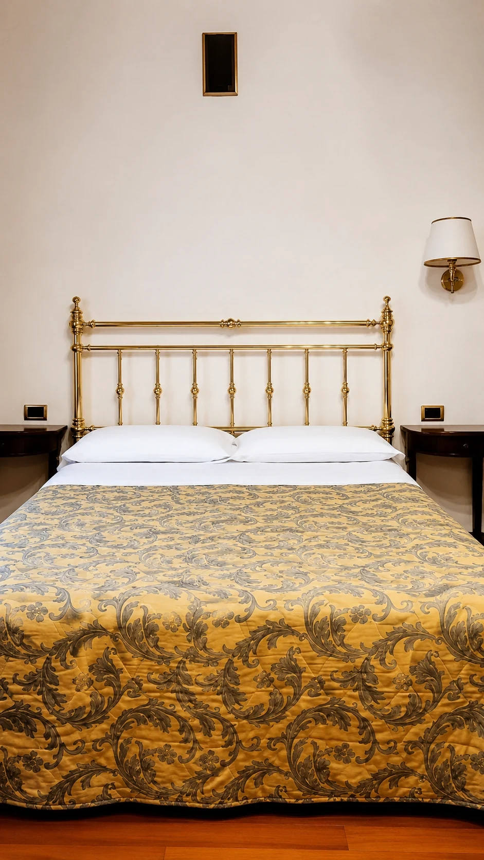 Il letto matrimoniale in ferro e ottone sotto il soffitto alto della Stanza dei Cassettoni