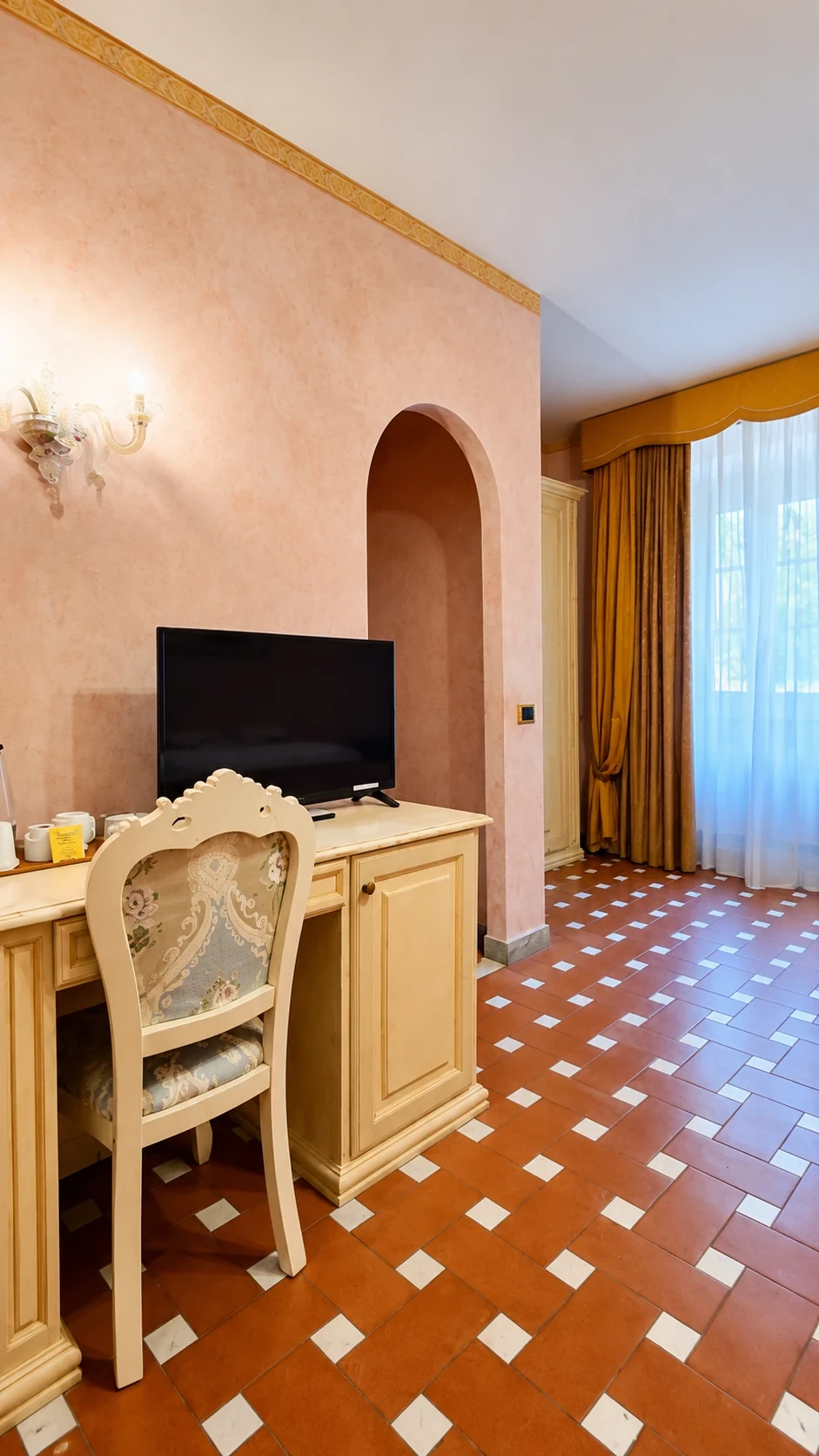 Lo scrittoio chiaro con televisore e tisaniera nella Camera 206, accanto all'apertura ad arco
