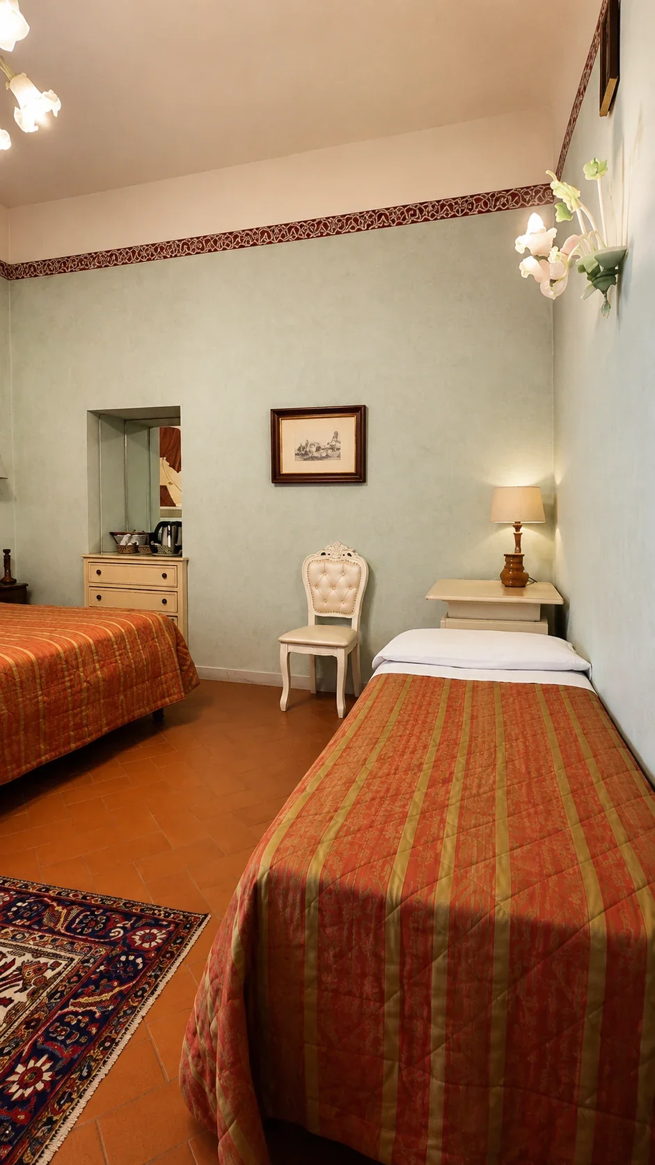 Il letto matrimoniale e il letto singolo sotto il fregio floreale della Camera 210