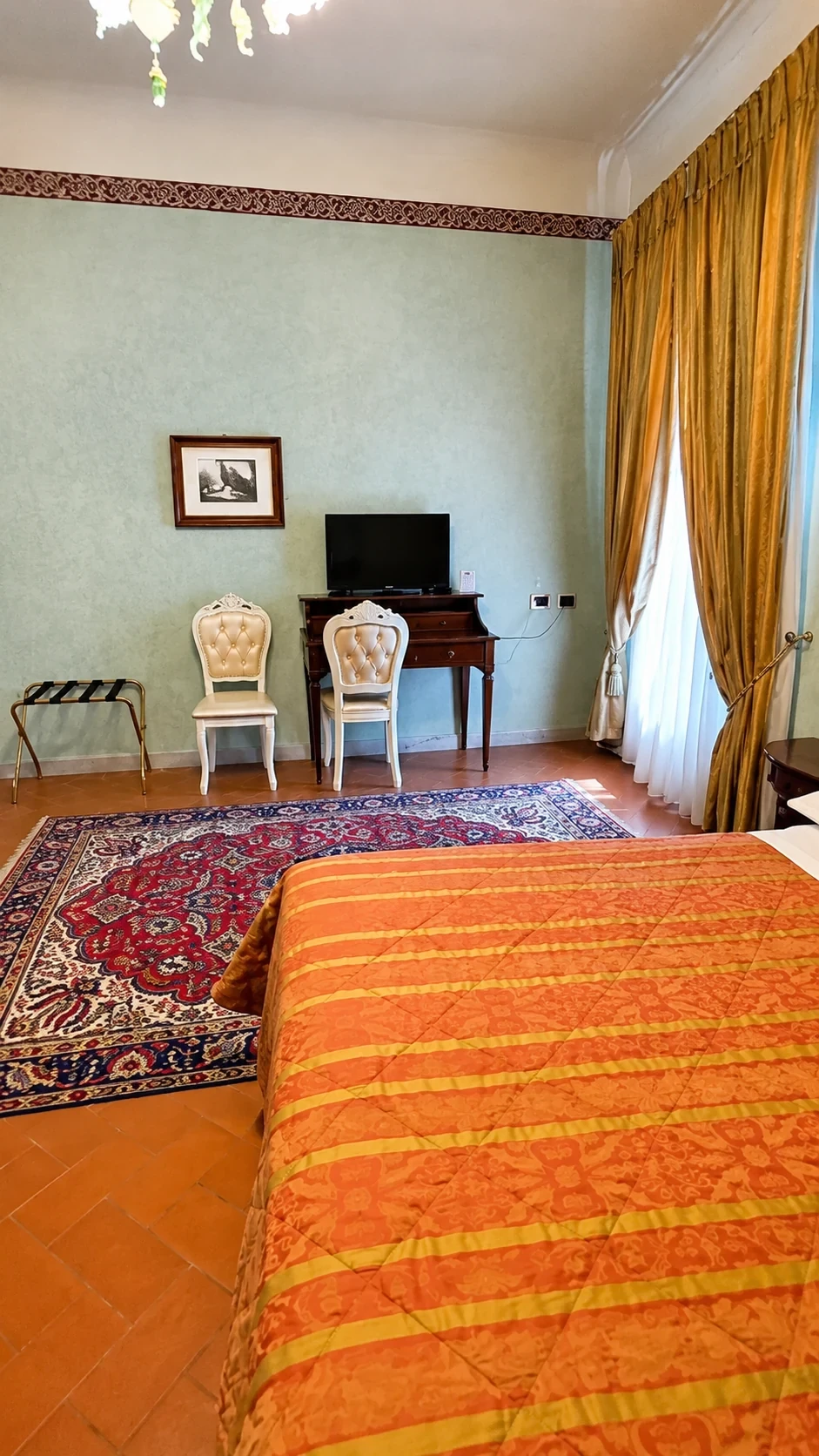 La Camera Michelozzi vista dal letto, con tappeto persiano, scrittoio d'epoca e finestra luminosa