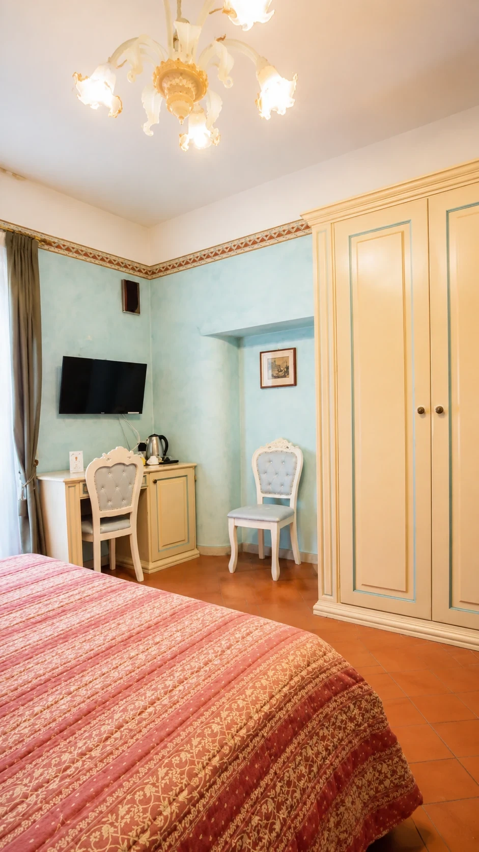 L'armadio chiaro e la poltrona imbottita accanto al letto nella Camera 211