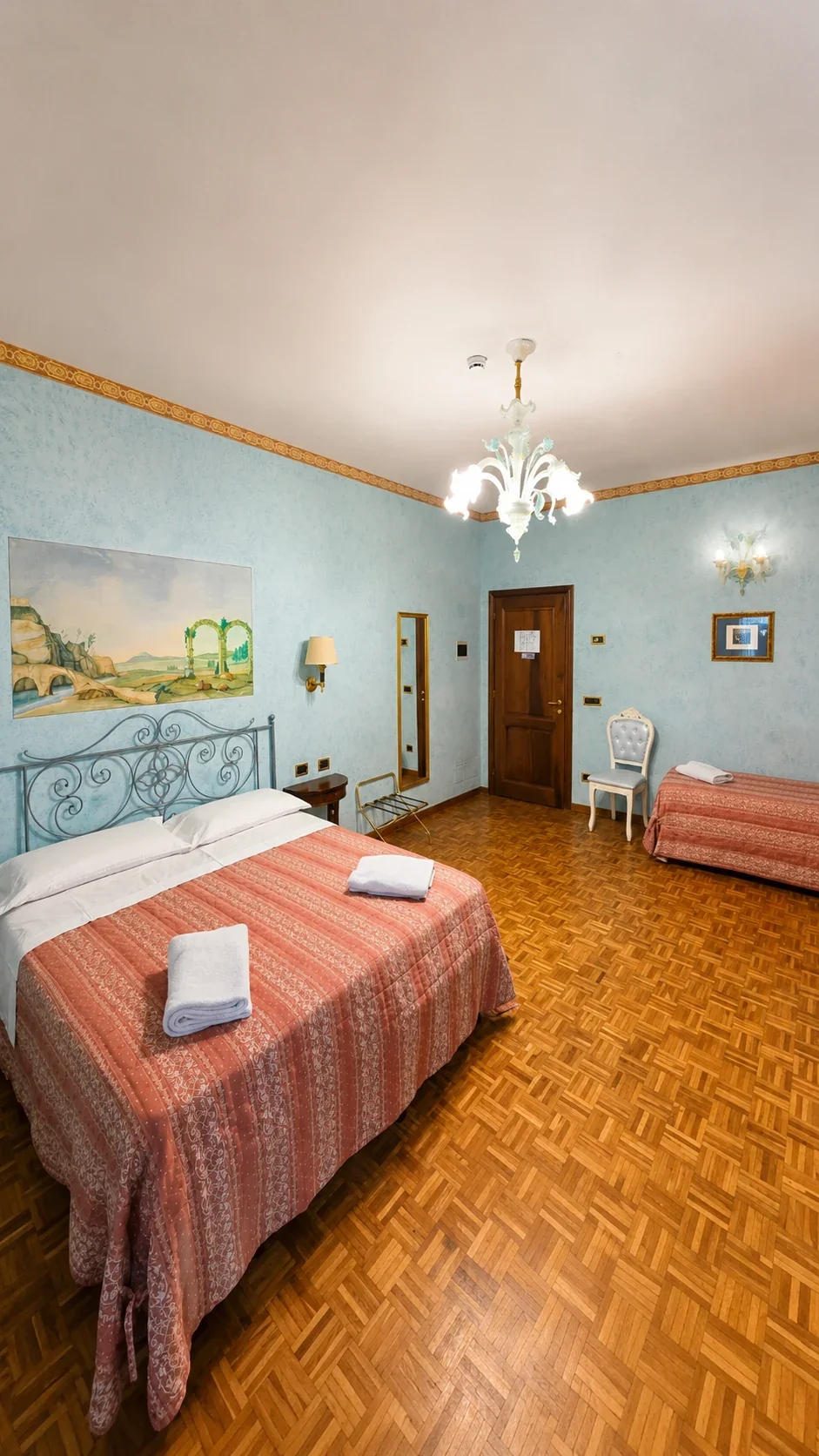 Il letto matrimoniale e il letto singolo della Camera Pandia sotto il lampadario in vetro