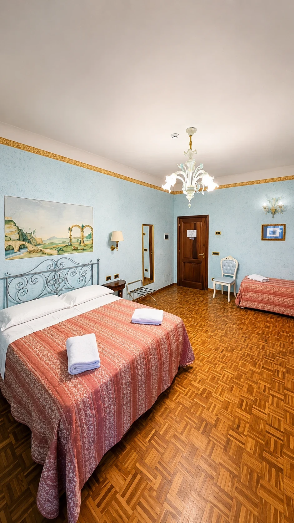La Camera Pandia vista dal letto, con il dipinto murale, la porta e il pavimento in legno