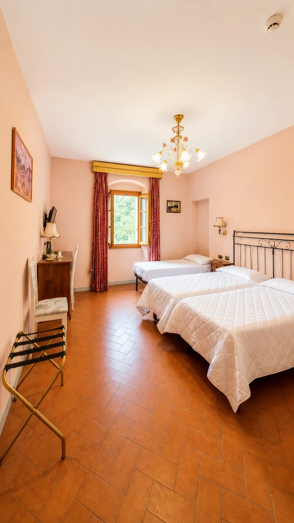 La Camera 403 con pareti rosa tenue, due letti, pavimento in cotto e finestra tra le tende dorate