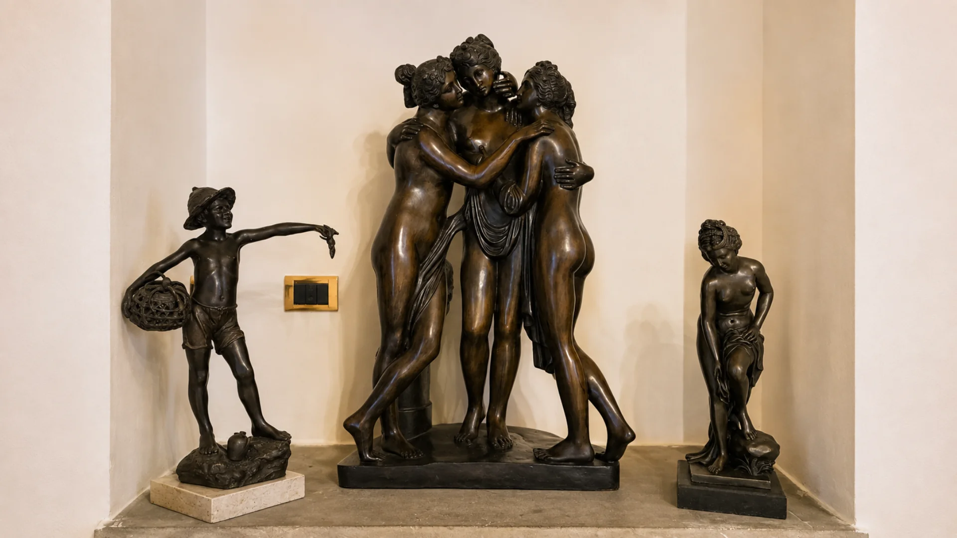 Bronze sculptures in the alcove of a suite: the Three Graces in the middle, a fisherboy with his basket on the left and a female figure on the right