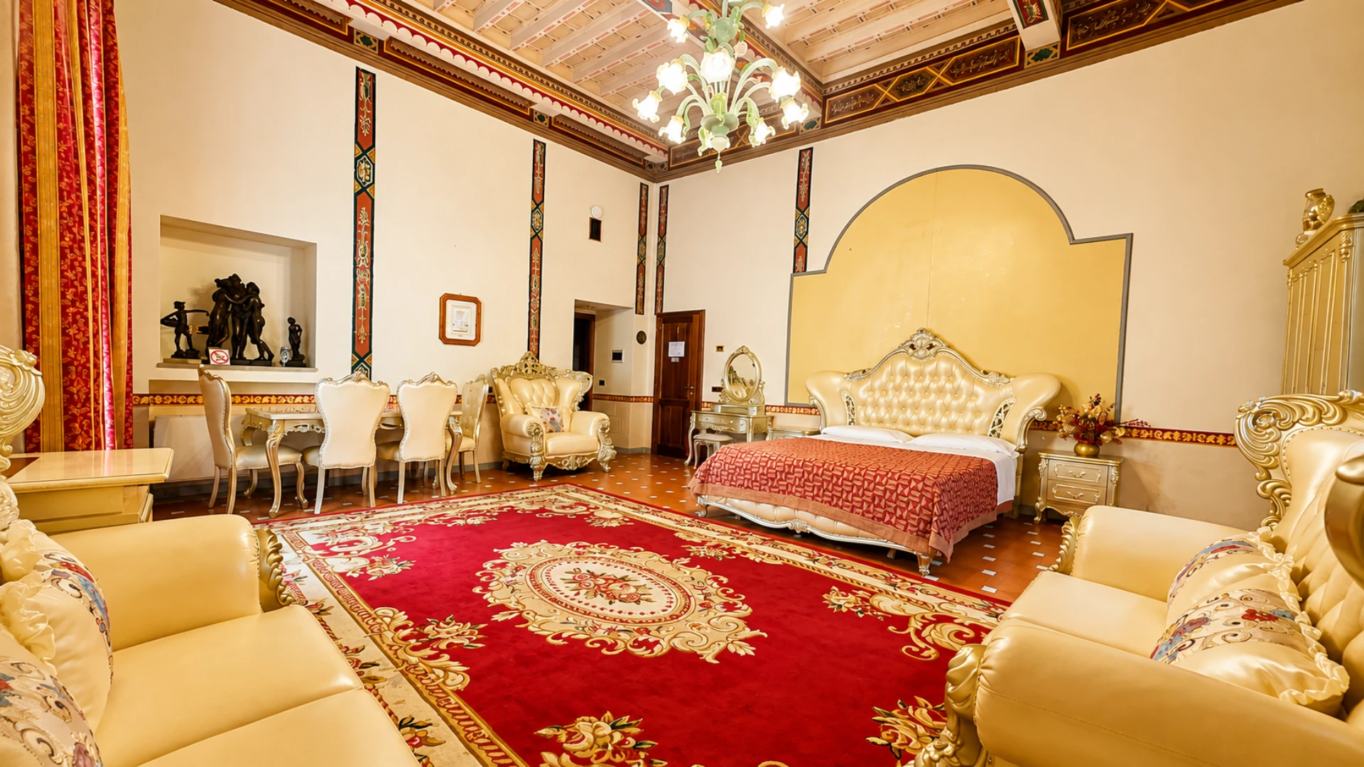 The Junior Suite seen from the door: painted beamed ceiling, glass chandelier, dining table and the double bed at the far end