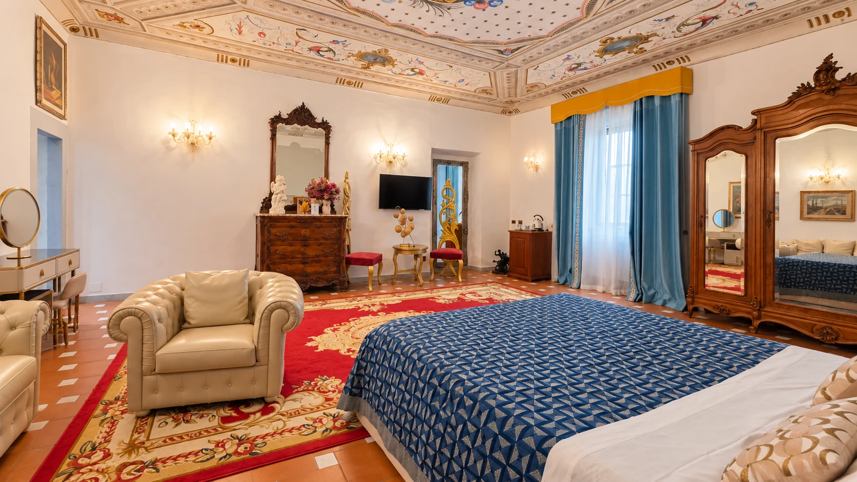 The Junior Suite with its double bed, leather armchair, wooden furniture and frescoed ceiling