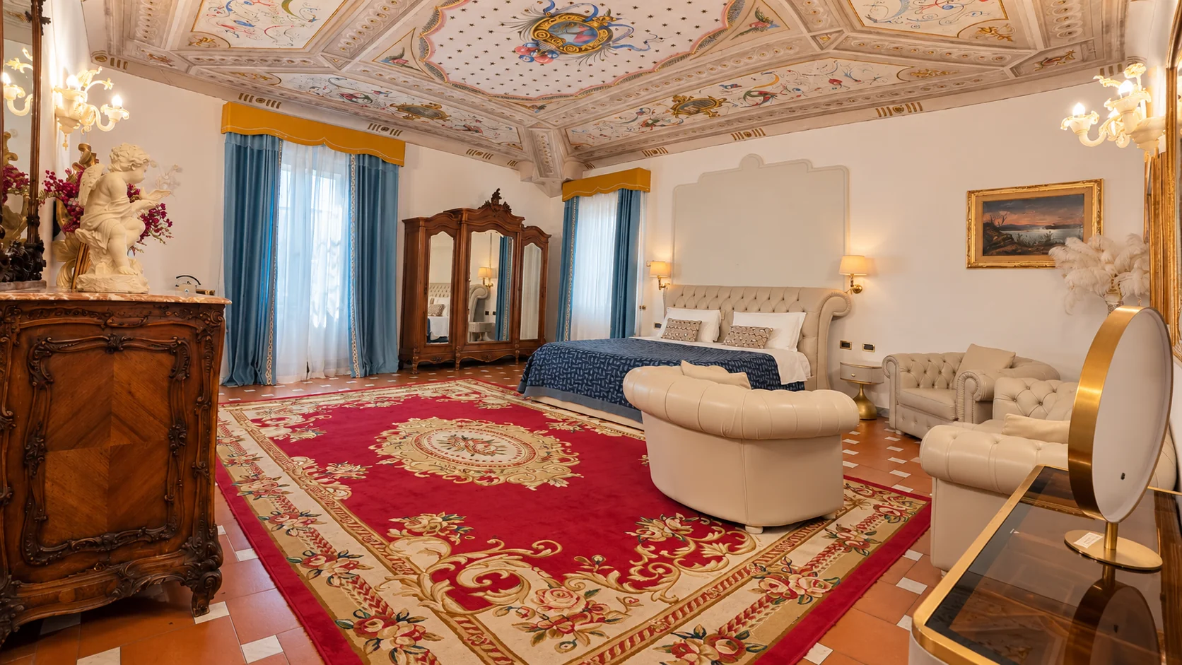The Junior Suite with its double bed, sitting area, red rug and frescoed ceiling