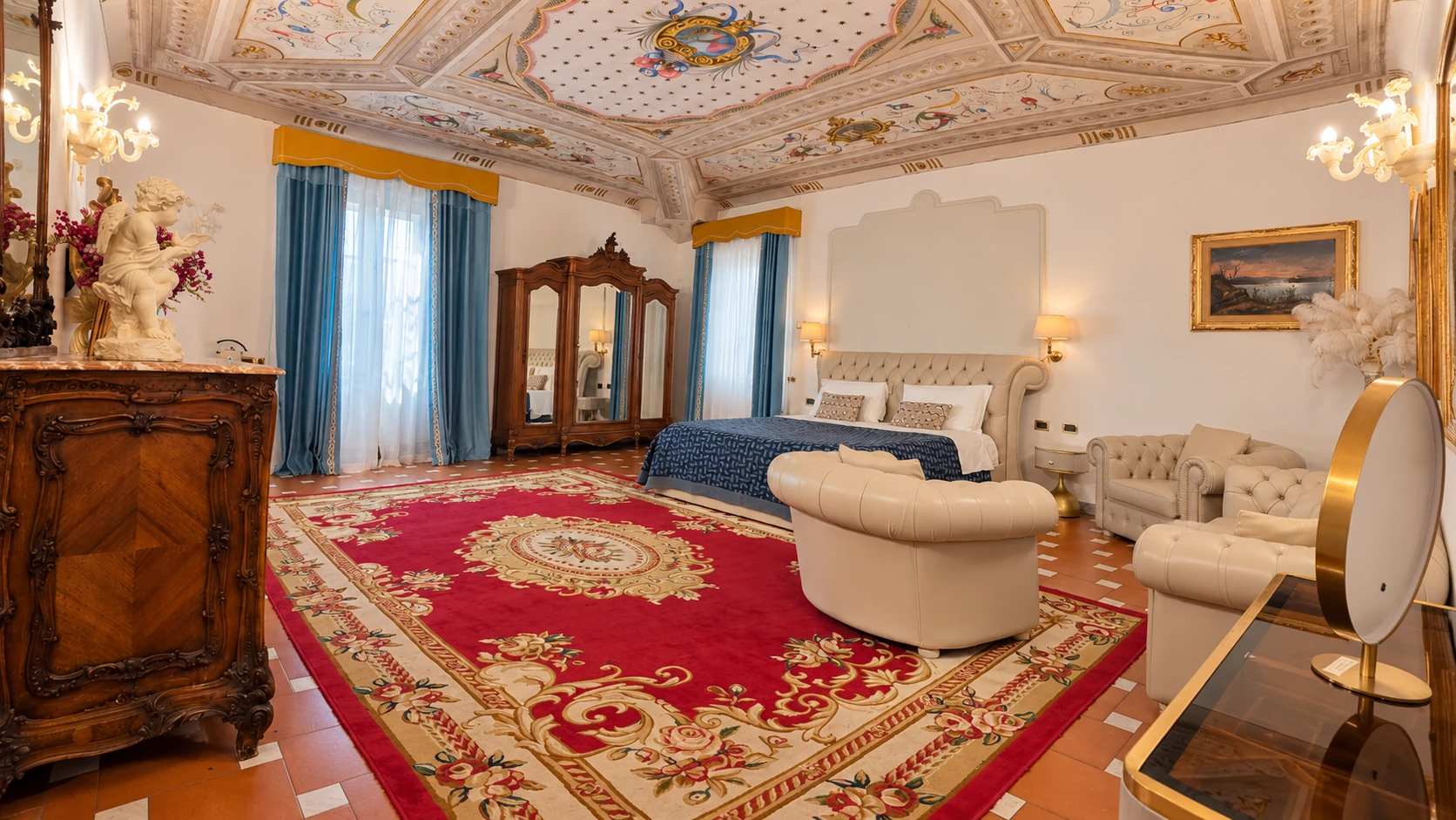 The Junior Suite with its double bed, sitting area, red rug and frescoed ceiling