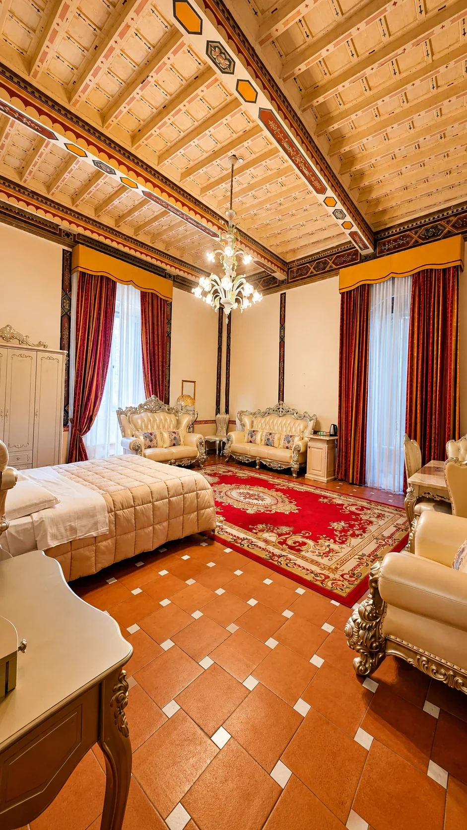 La Suite Ughi con letto, salotto, grandi finestre e tappeto porpora sotto il soffitto decorato