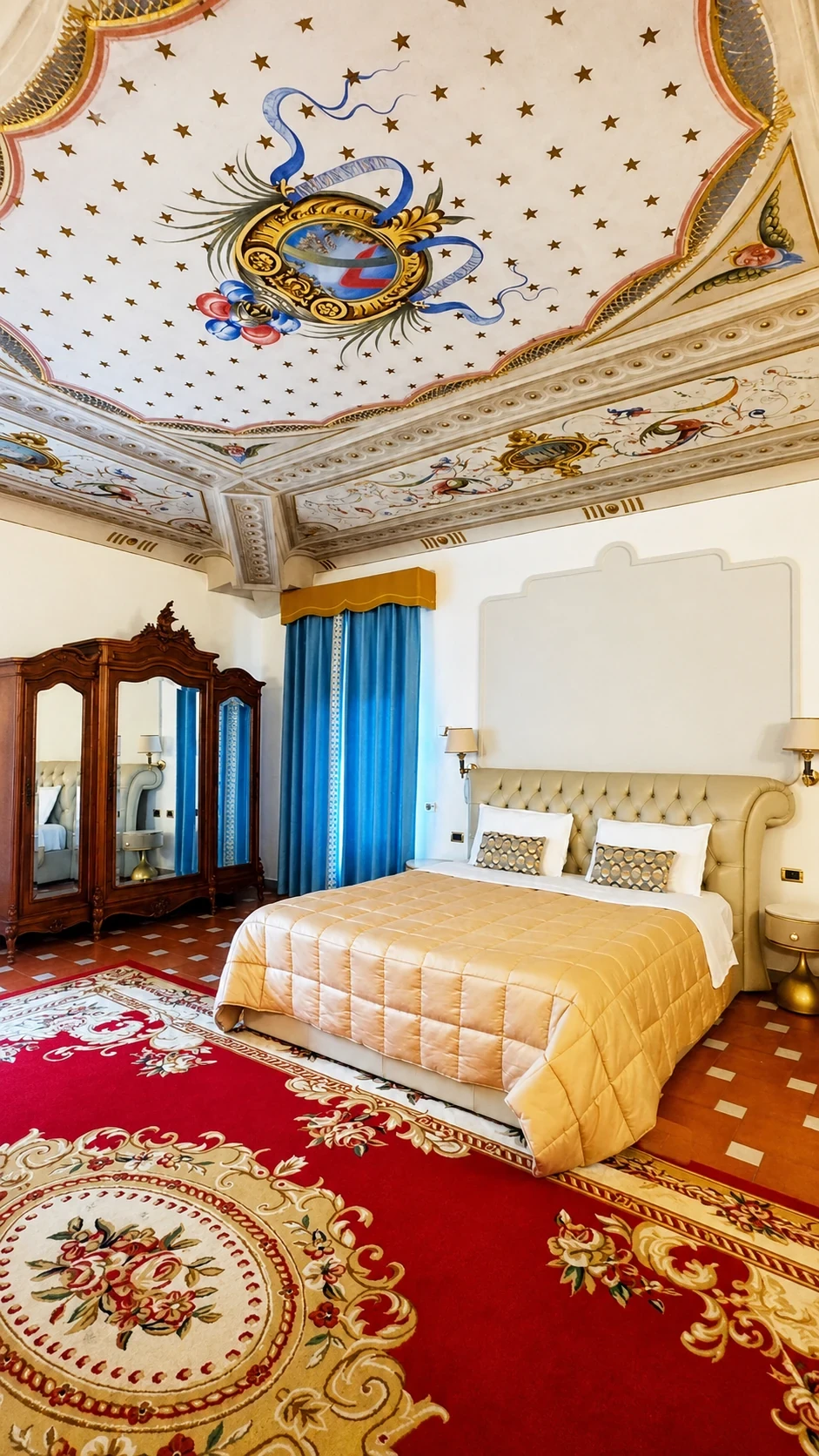 Il letto della Junior Suite 201 sotto il soffitto affrescato, con armadio antico e tende azzurre