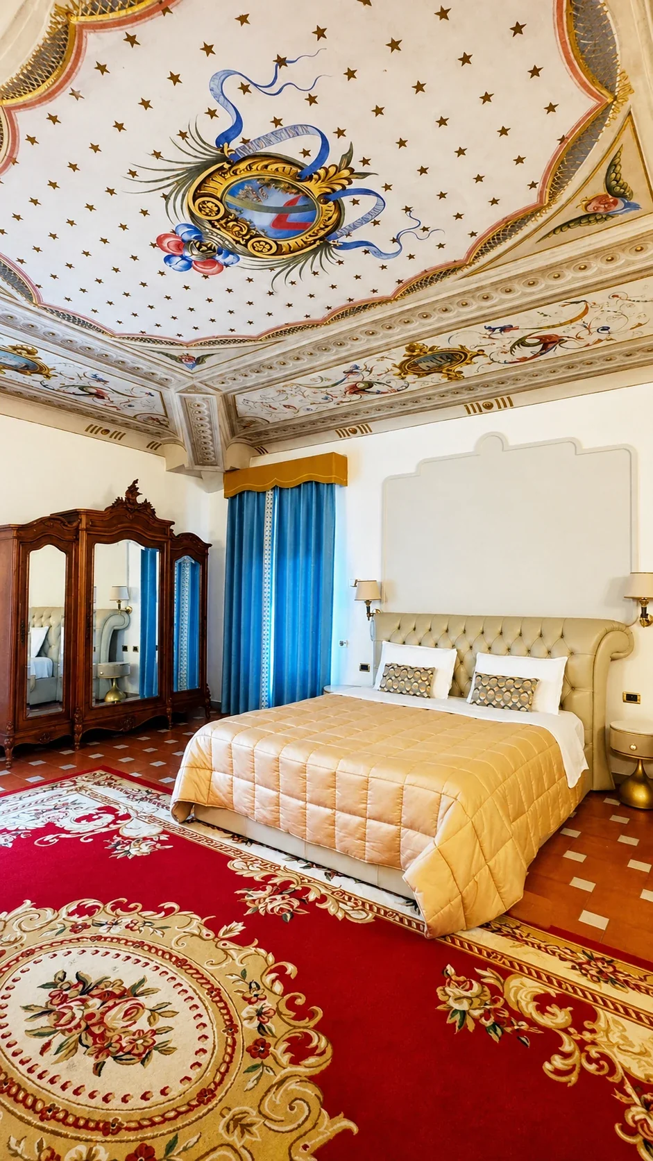 Il letto della Junior Suite 201 sotto il soffitto affrescato, con armadio antico e tende azzurre