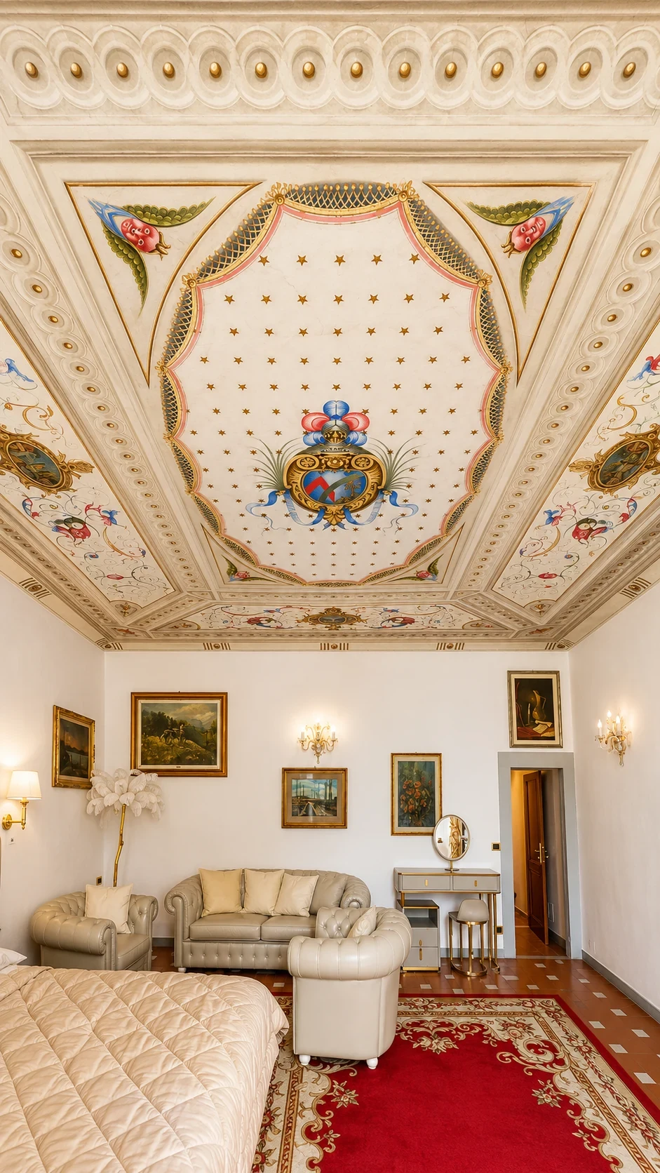 Il soffitto affrescato della Suite Ambrogi sopra il letto e il piccolo salotto con poltrone chiare