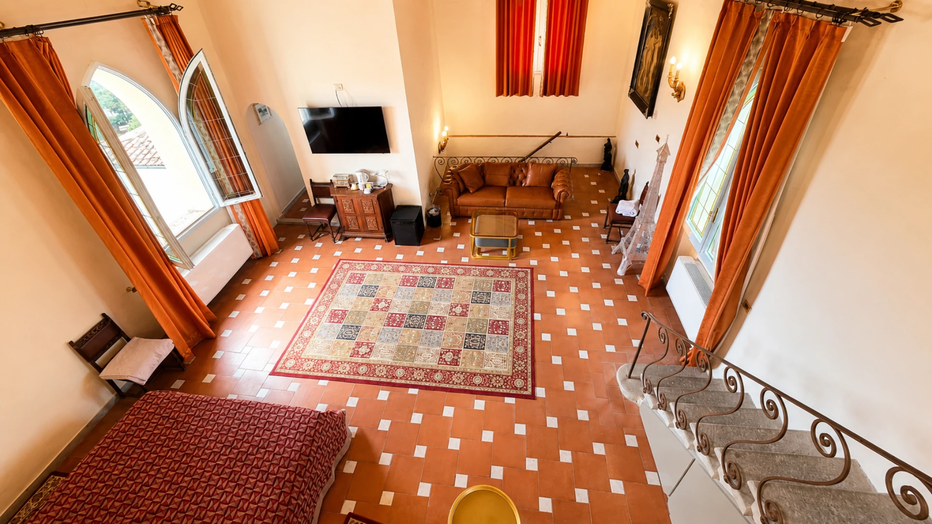 The King deluxe seen from the mezzanine: the rug in the middle, the leather sofas and the two arched windows