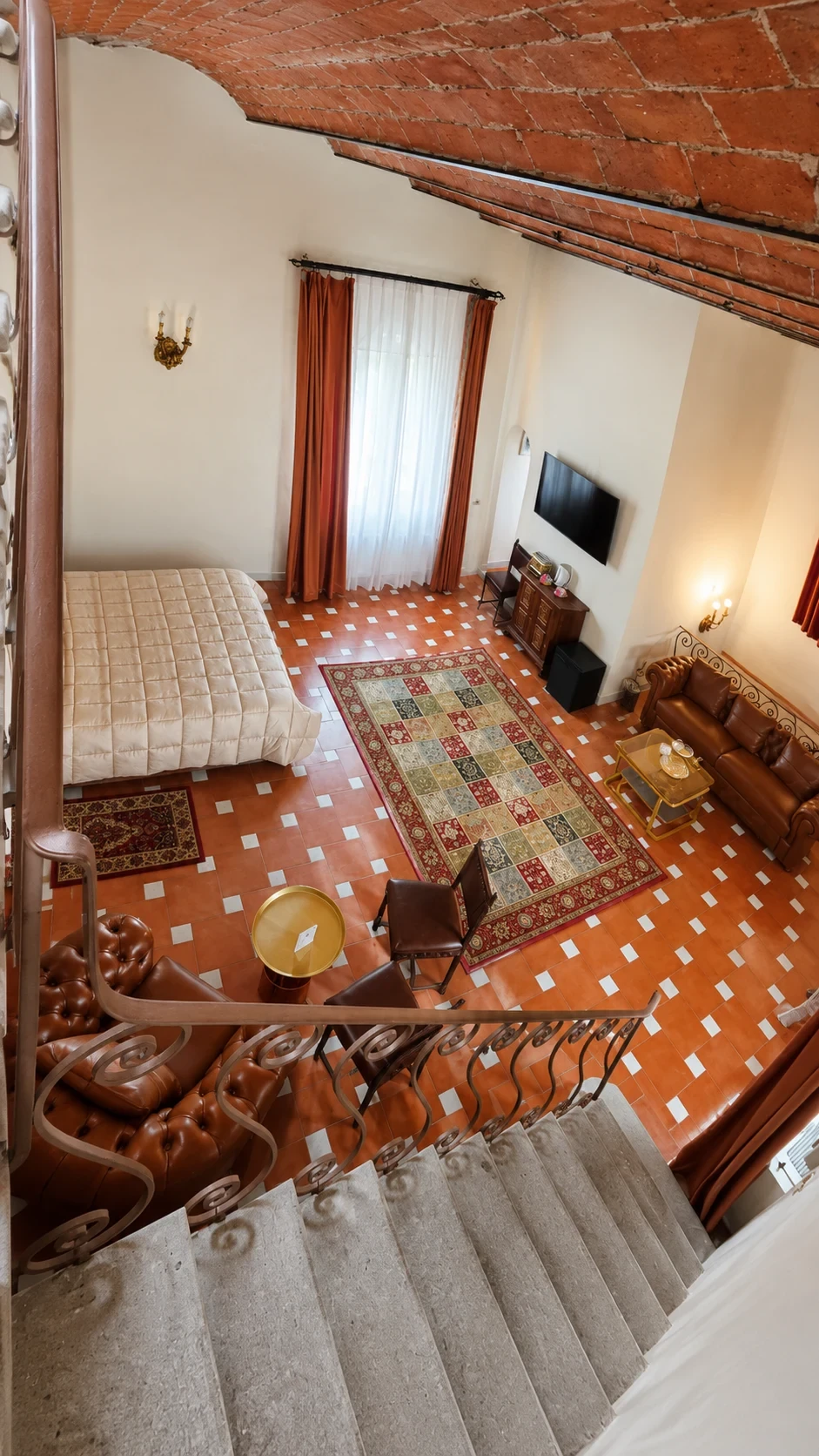 Il letto, il tappeto multicolore e il salotto Chesterfield della Camera 218 visti dal pianerottolo
