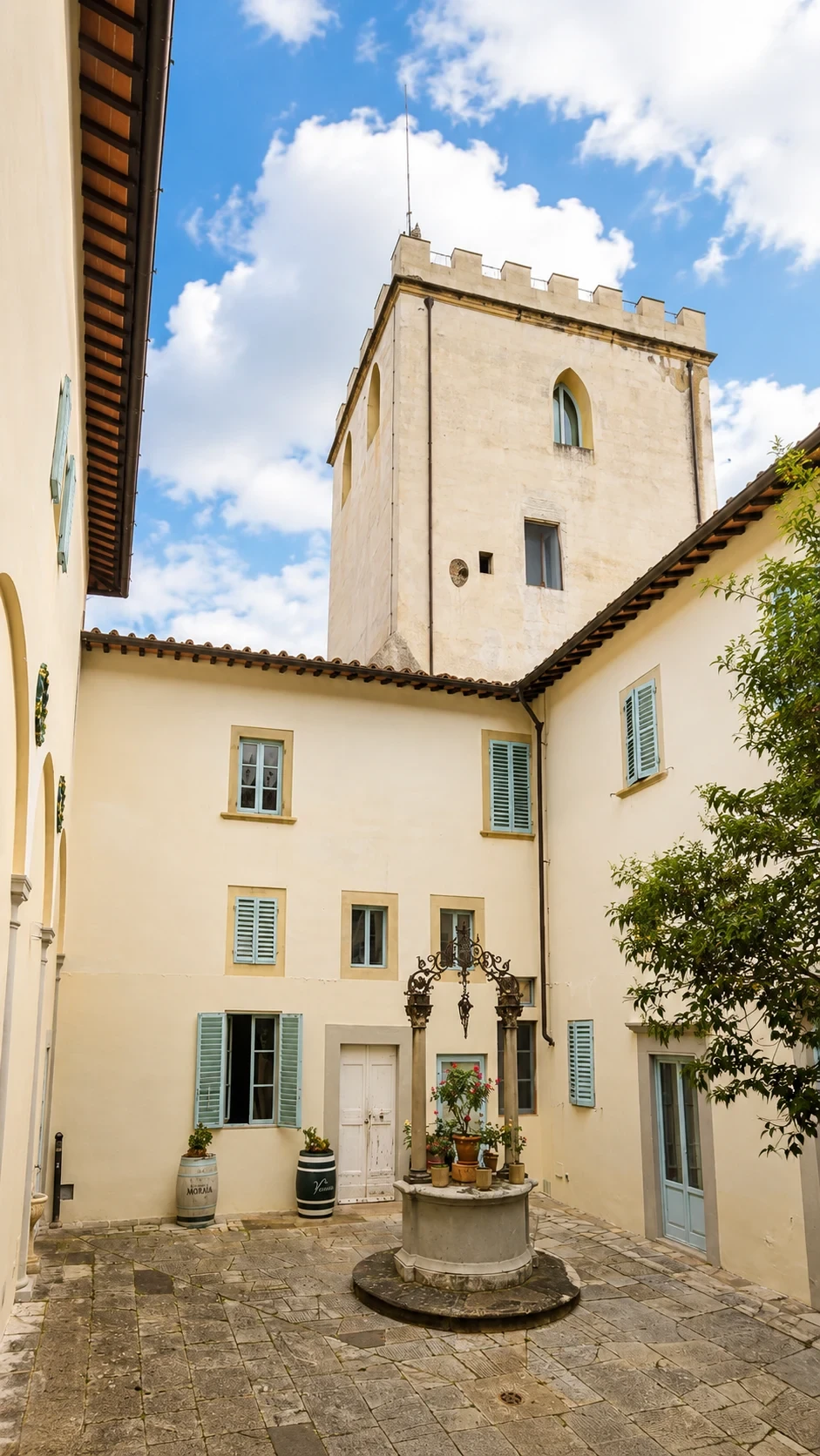 La torre merlata e il cortile storico di Villa Camporella osservati dal giardino