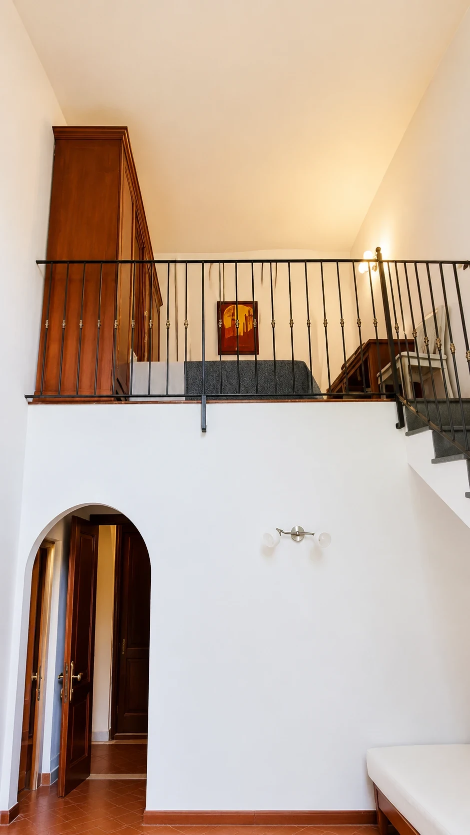 Il soppalco del Loft 301 con ringhiera in ferro, divano letto e scala laterale