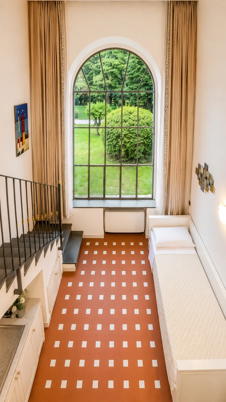 Il letto singolo del Loft 302 accanto alla finestra sul prato e alla scala per il piano superiore