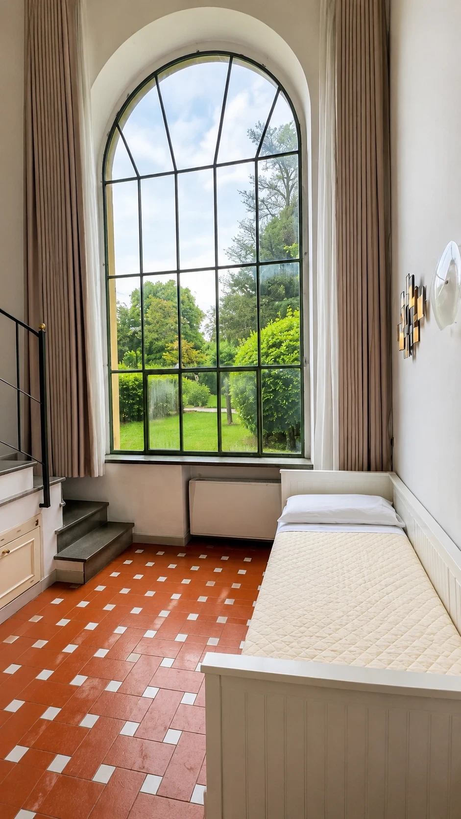 La grande finestra del Loft Cirene aperta sul parco con il letto raccolto accanto alla parete