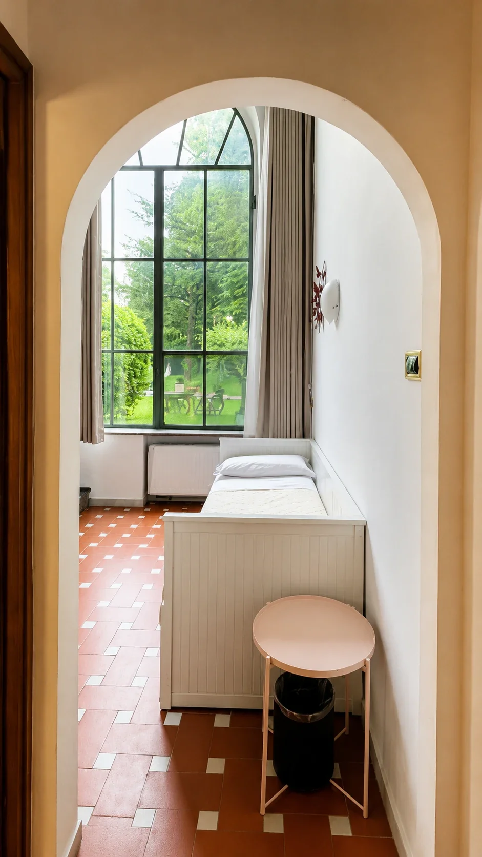 Il letto singolo al piano inferiore del Loft 303 davanti alla finestra alta sul giardino