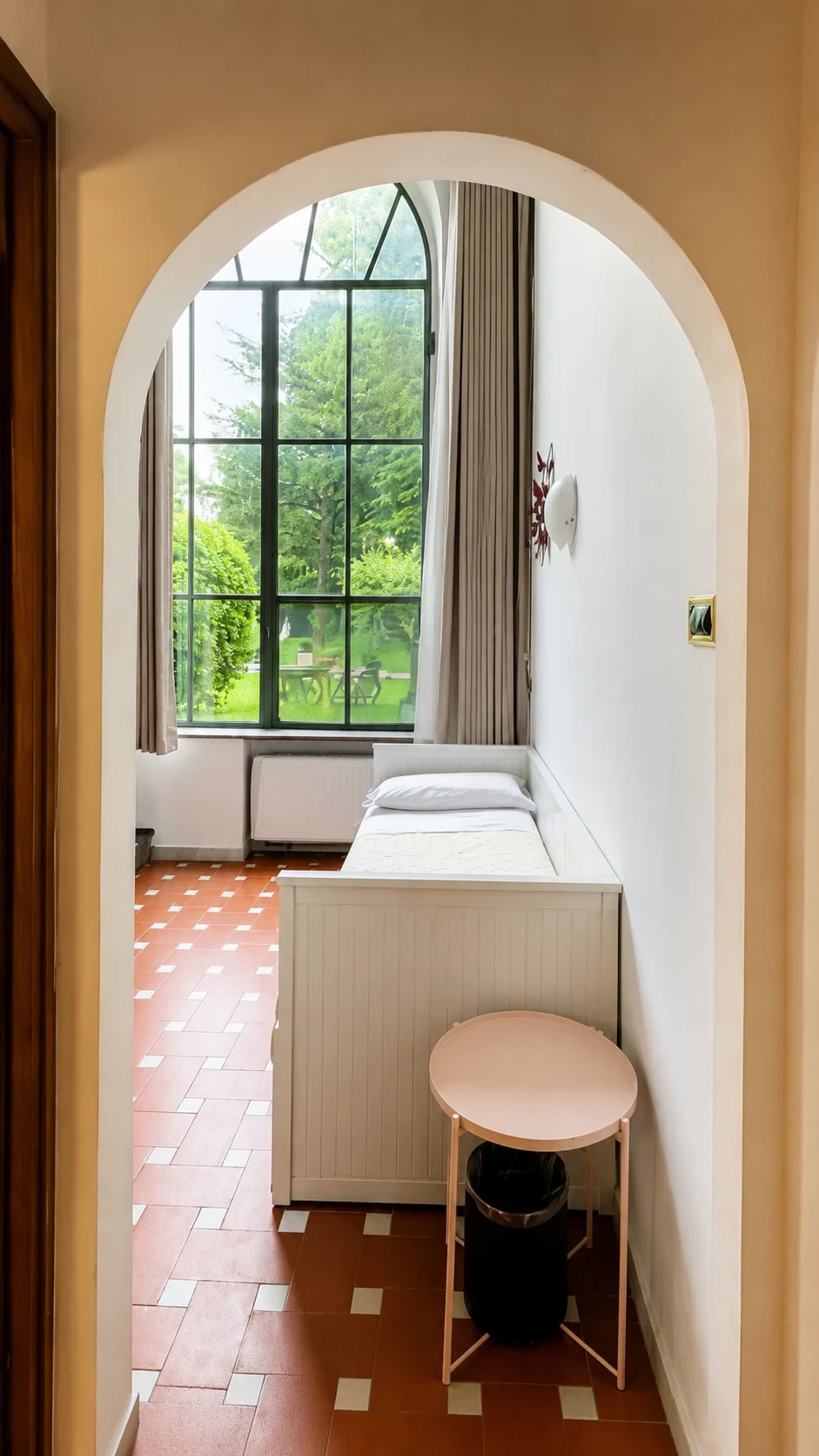 Il letto singolo al piano inferiore del Loft 303 davanti alla finestra alta sul giardino