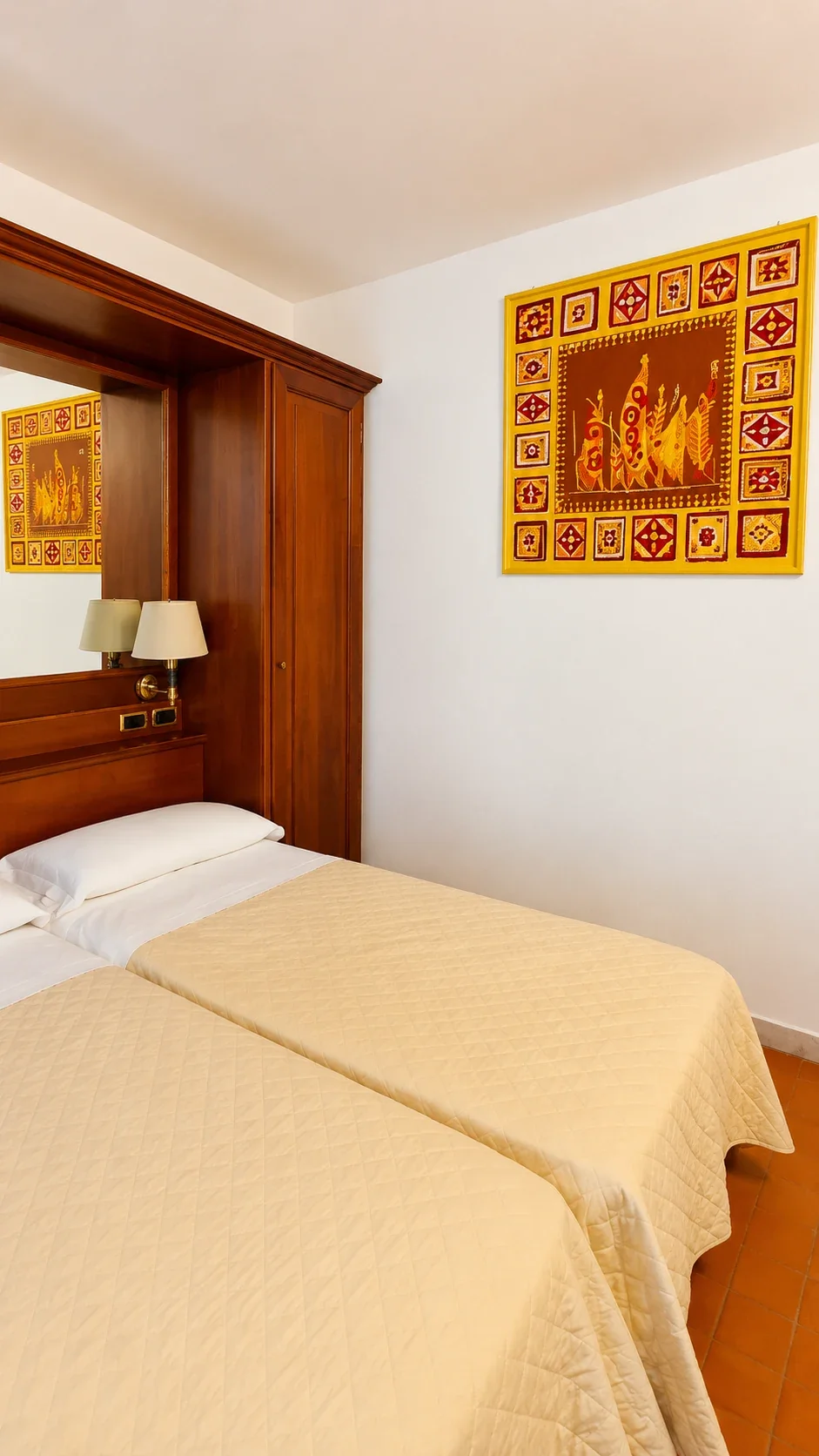 Il letto del Loft 303 sotto la testata in legno e un pannello decorativo dai colori caldi