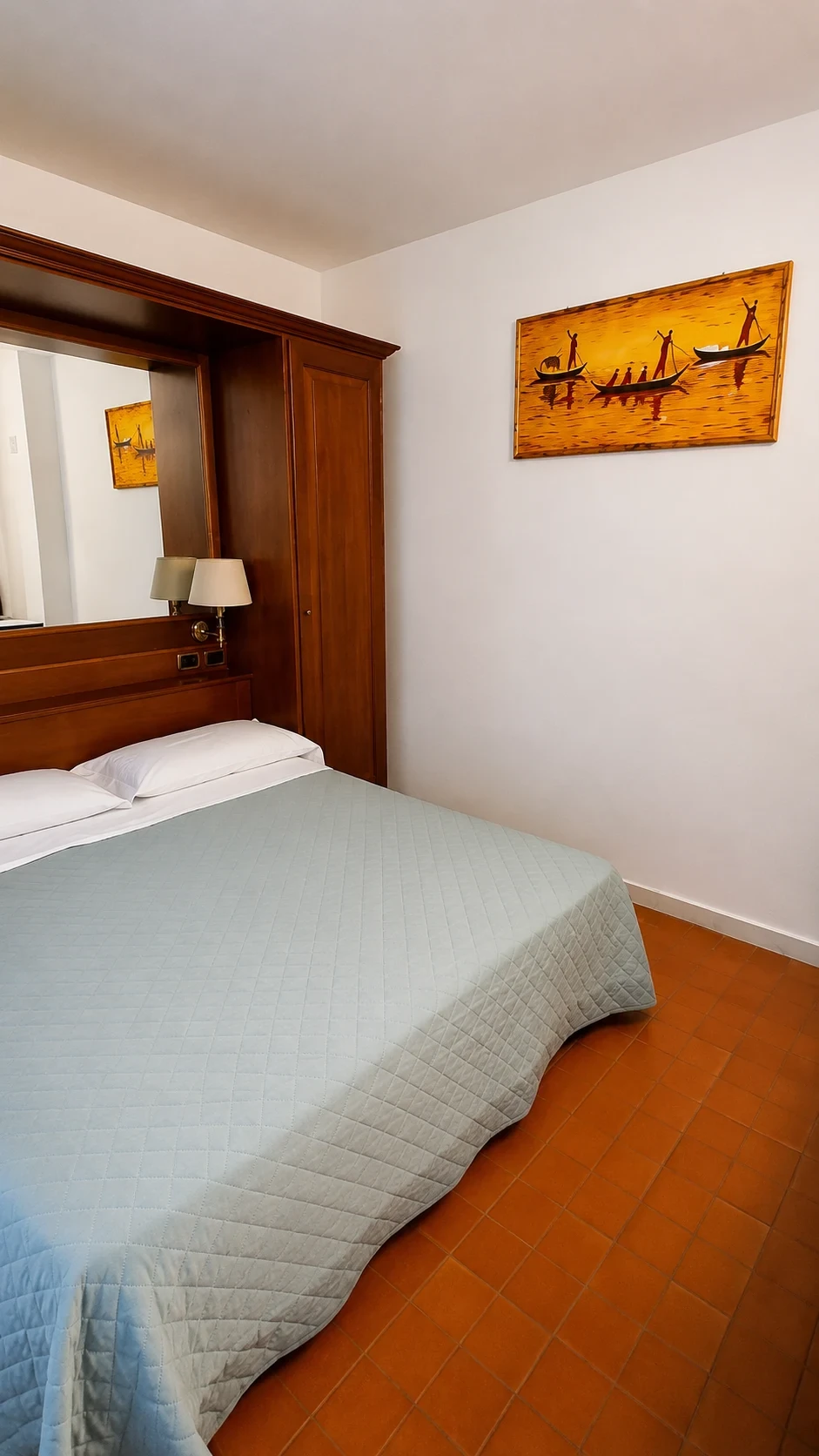 Il letto del Loft 304 con testata in legno, lampada da lettura e tessuti verde chiaro