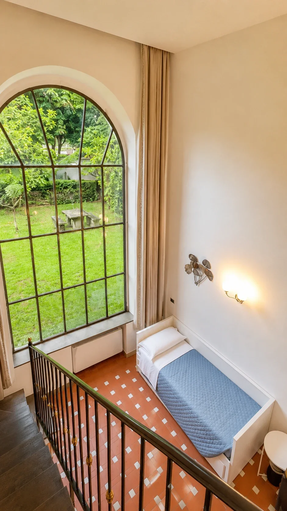 La grande finestra del Loft Calipso illumina la parete con applique e il prato esterno