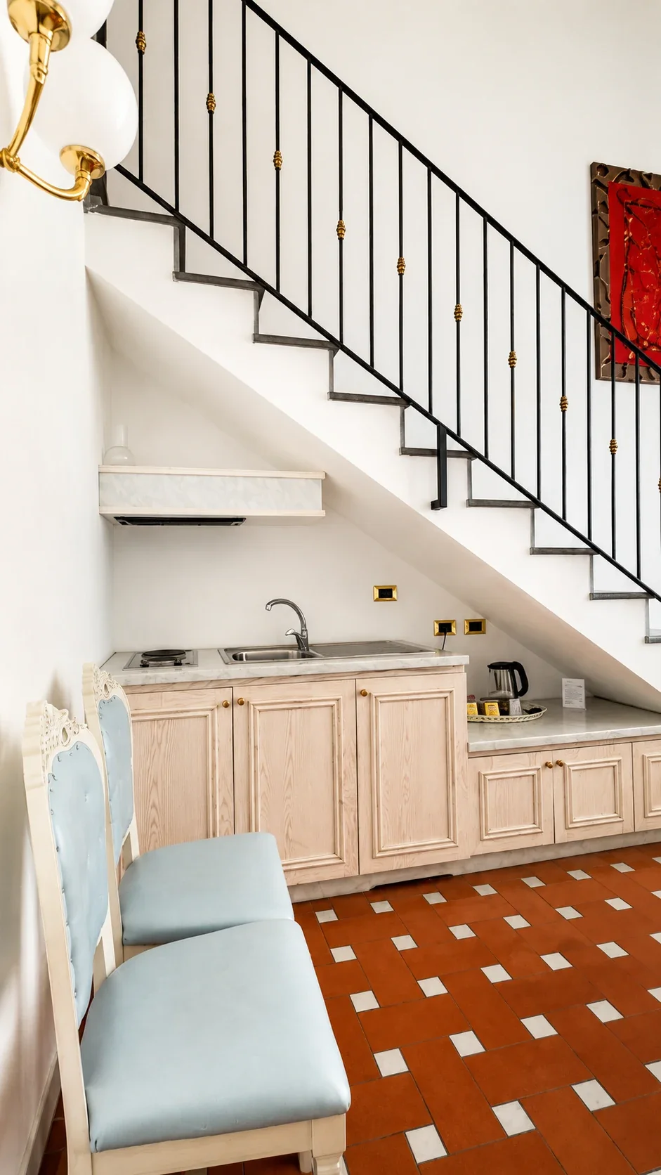 La cucina del Loft 305 sotto la scala con piano cottura, lavello e piano in marmo