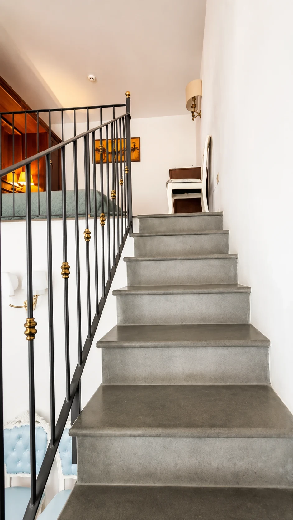 La scala in pietra del Loft 305 sale verso il piano notte tra ringhiere nere e dettagli dorati