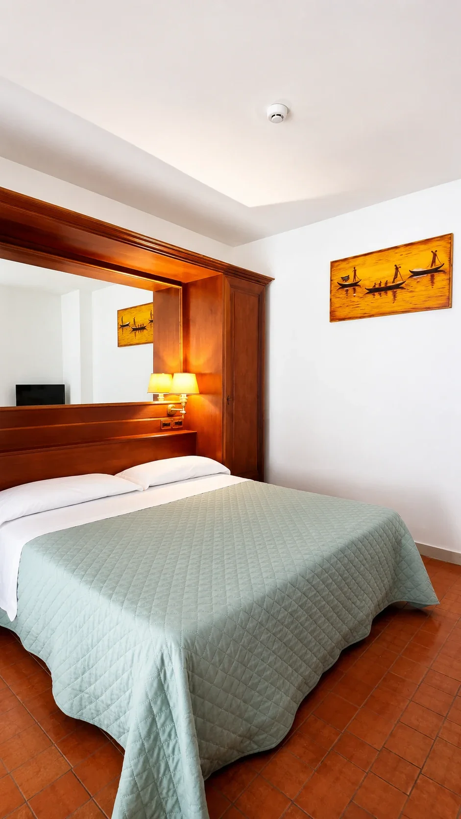 Il letto matrimoniale del Loft 305 con testata in legno, lampade calde e pannelli decorativi
