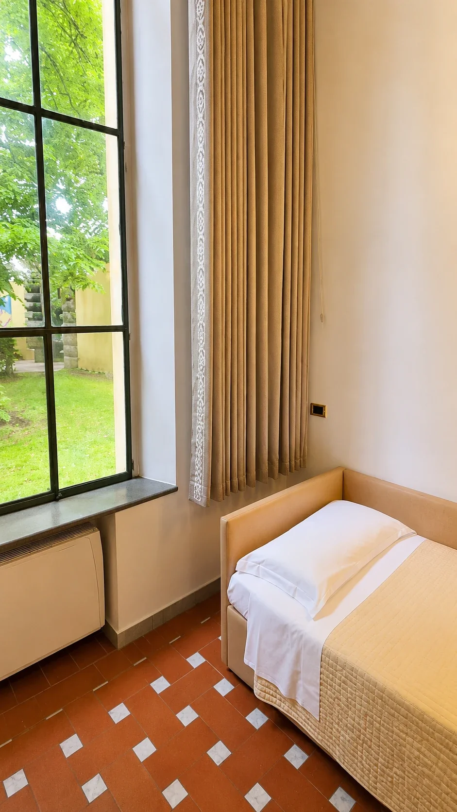La finestra del Loft 306 aperta sul prato con il letto singolo raccolto accanto alla parete