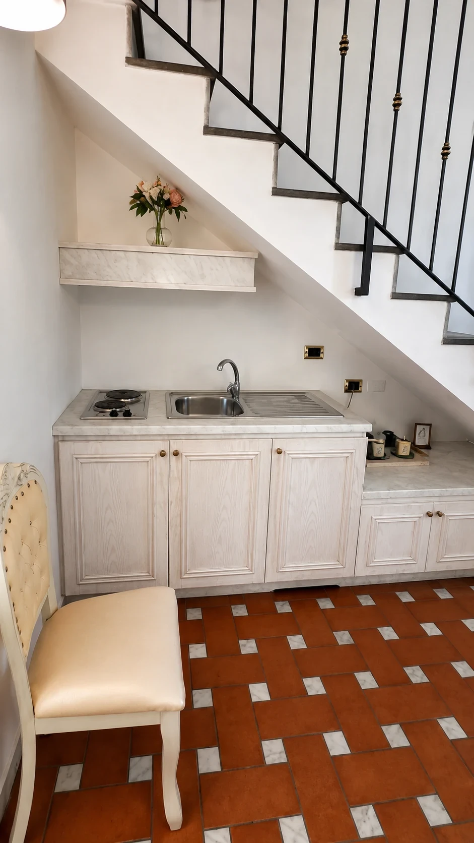 La cucina chiara del Loft 306 sotto la scala con piano cottura, lavello e armadietti