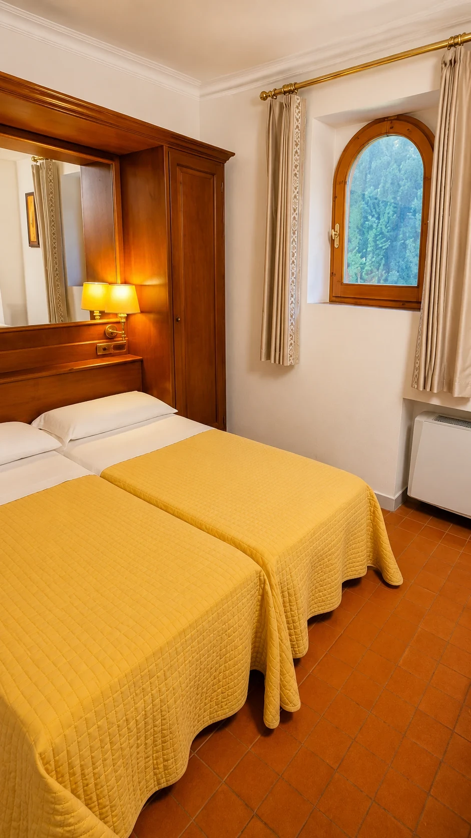 I due letti del Loft 308 con copriletti gialli, testata in legno e finestra laterale