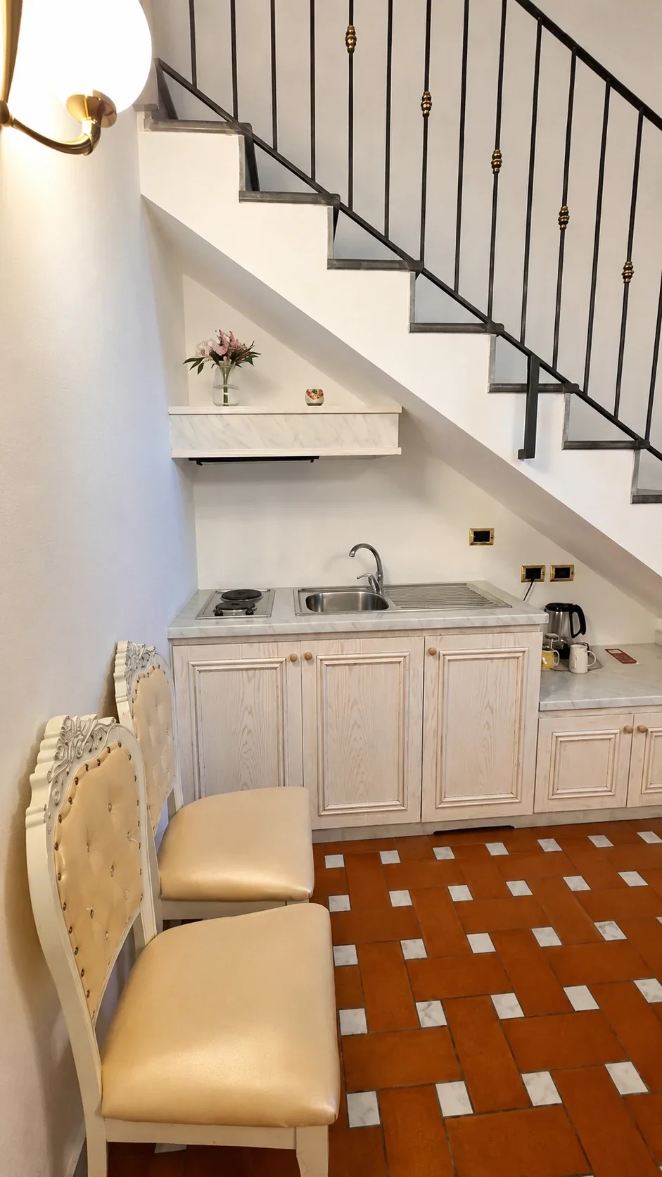 La cucina bianca del Loft 308 sotto la scala con lavello e piano cottura