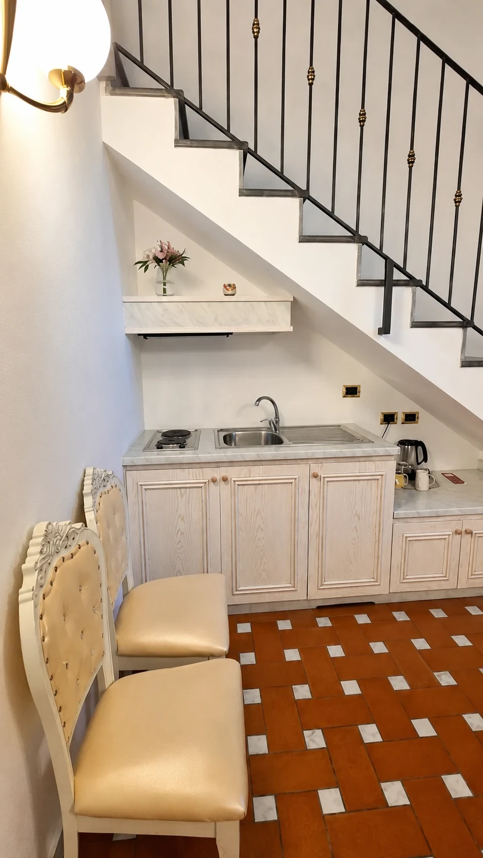 La cucina bianca del Loft 308 sotto la scala con lavello e piano cottura