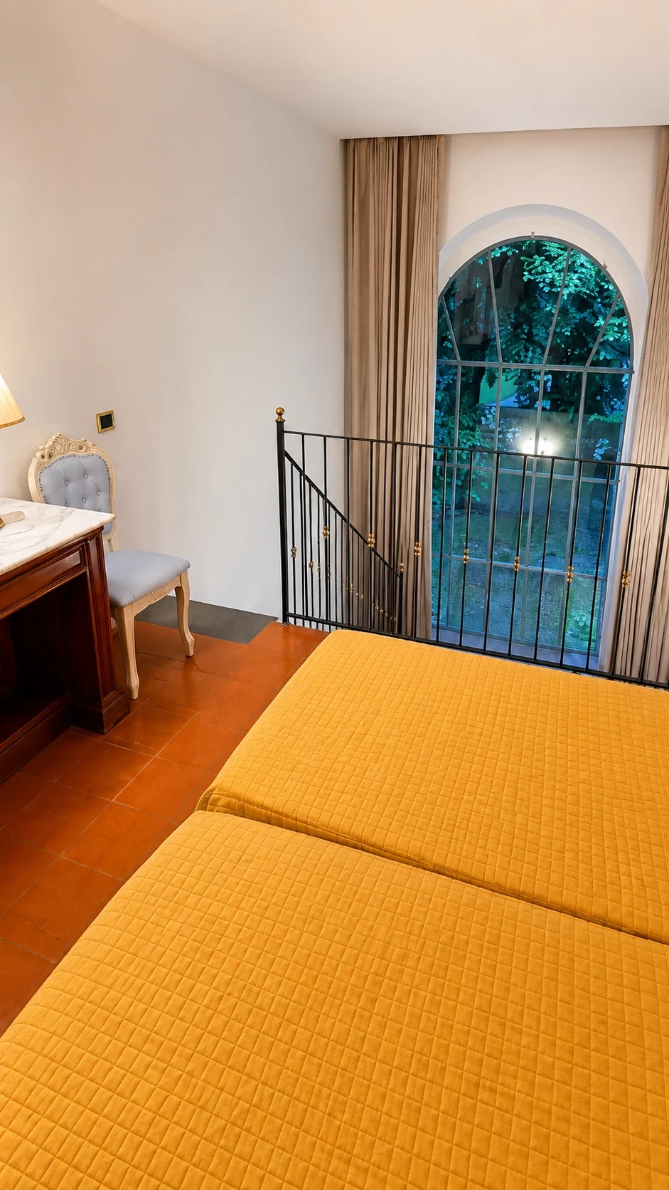 Il letto del Loft 308 accanto alla ringhiera del soppalco e alla grande finestra illuminata sul giardino