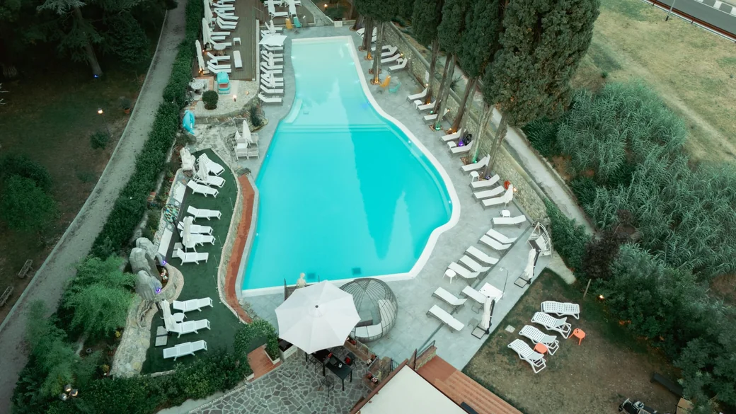The pool from above at dusk, loungers all around and the lights on