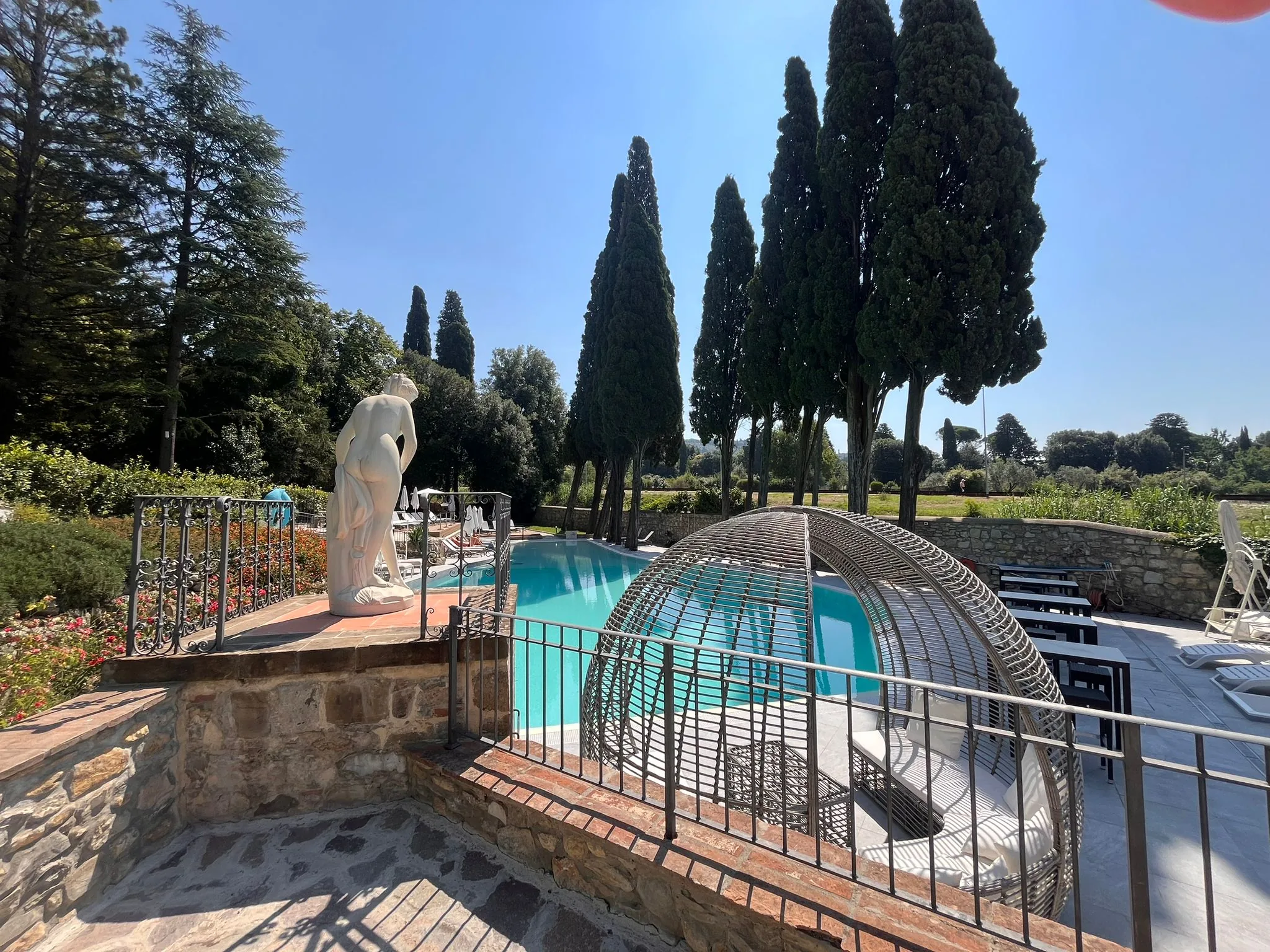 La piscina di Fantastic Garden fra i cipressi, con i lettini e il gazebo