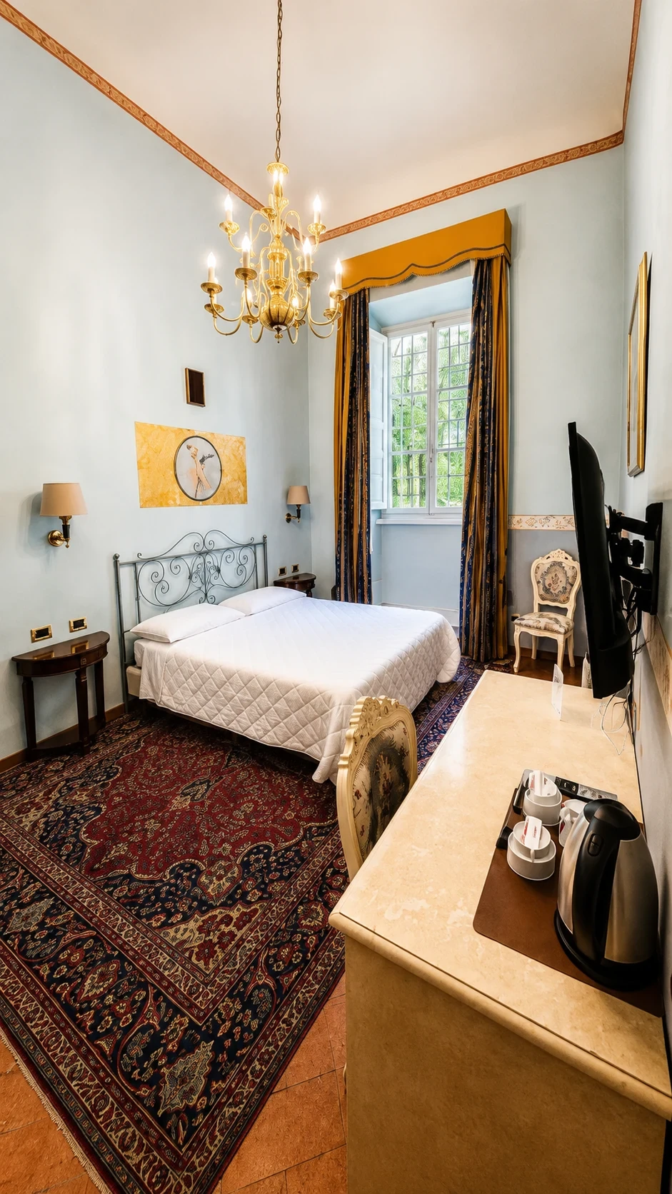 La Camera Premium 105 con letto in ferro battuto, tappeto rosso, scrittoio chiaro e pareti azzurre