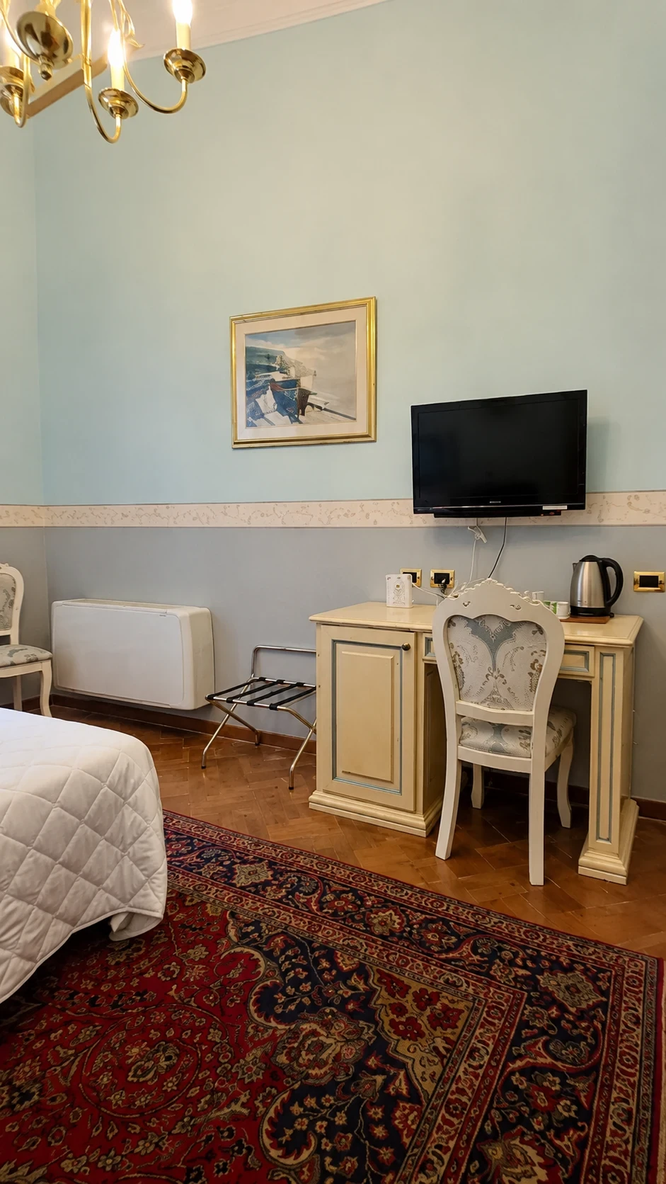 Lo scrittoio avorio, il televisore e il fregio decorativo azzurro della Camera 105