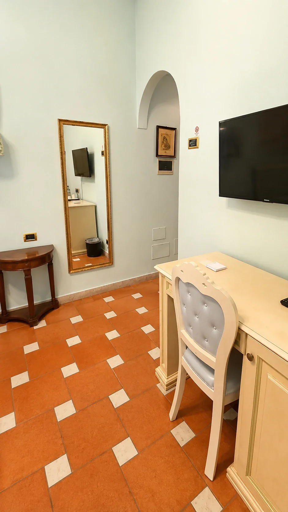 Lo scrittoio chiaro, lo specchio e il televisore nella Camera degli Amorini