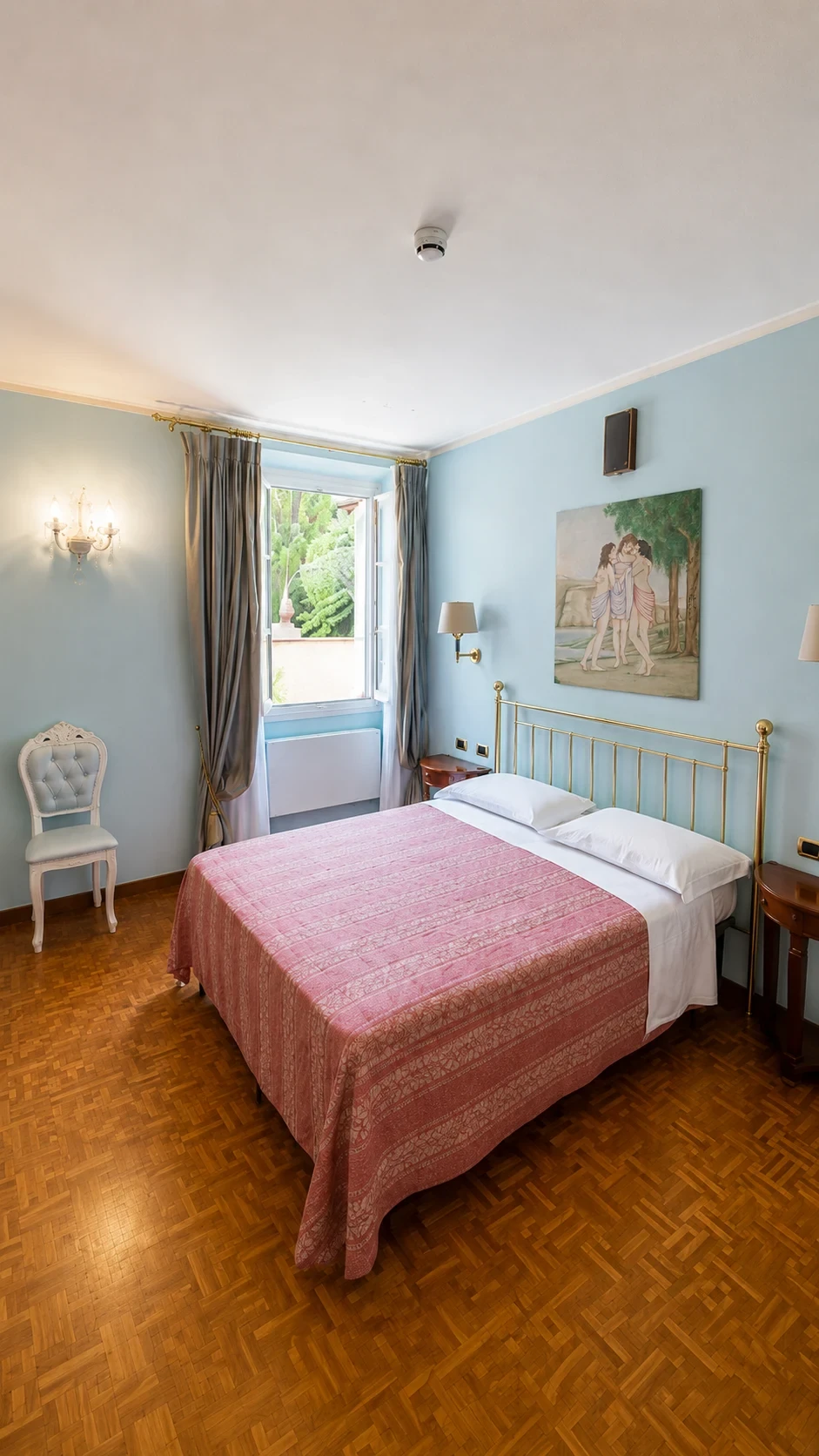 La Camera 204 dalle pareti azzurre con letto in ottone, dipinto mitologico e finestra sul chiostro