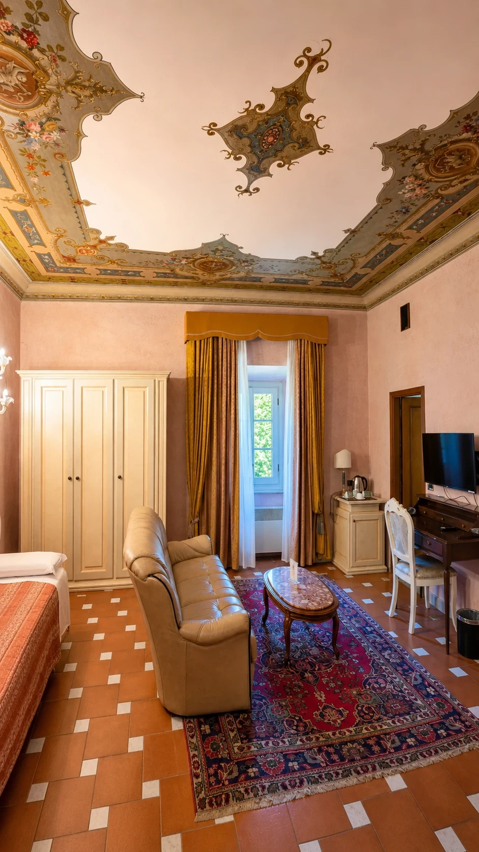 Il salotto con poltrone, tavolino e tappeto rosso sotto il soffitto decorato