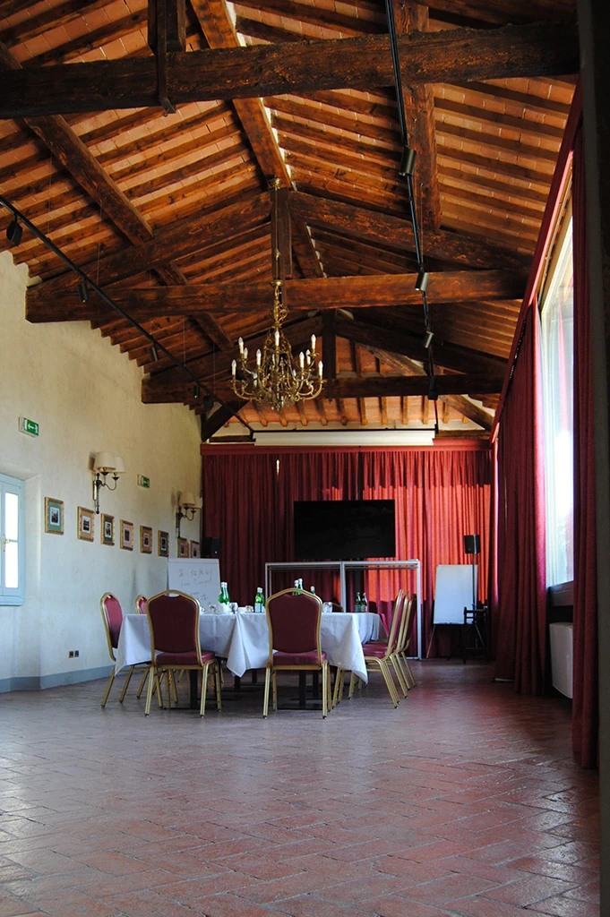 The hall set up for a course: a horseshoe of tables, a television and a flip chart under the beamed ceiling