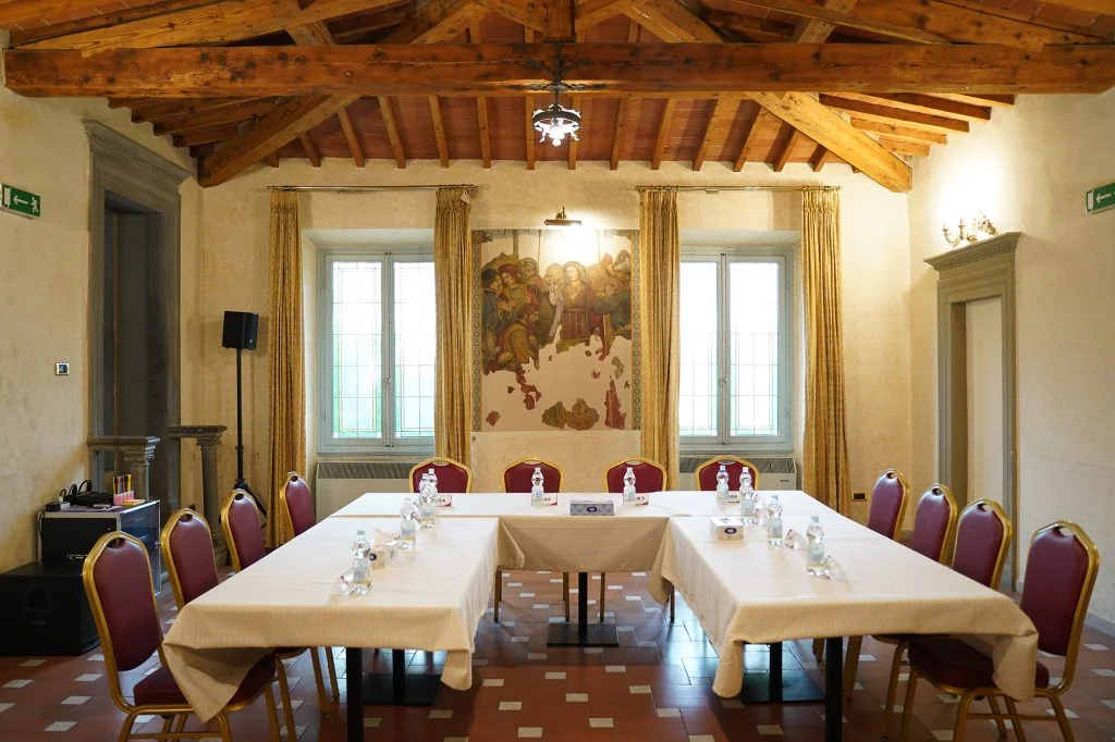 La Sala Riunioni con i tavoli a ferro di cavallo e le tovaglie chiare, davanti all'affresco fra le due finestre